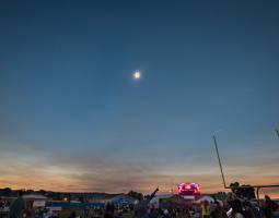 Photo of an bright eclipse in a twilight sky above a crowd of people
